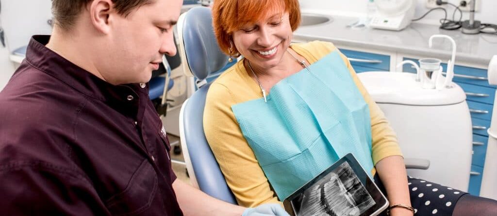 Female watching a tab with x-ray of teeth, and a doctor handling the tab and explaining the issues