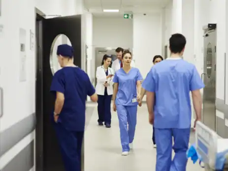 A busy hospital corridor with a team of doctors and nurses moving purposefully, illustrating the critical importance of efficient workflow and functional zoning in hospital design to avoid common planning errors.