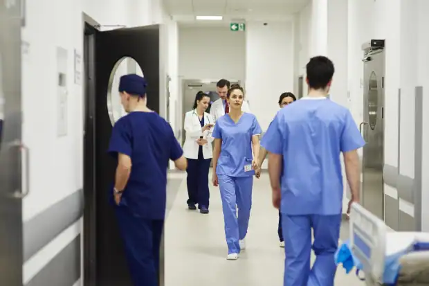 A busy hospital corridor with a team of doctors and nurses moving purposefully, illustrating the critical importance of efficient workflow and functional zoning in hospital design to avoid common planning errors.